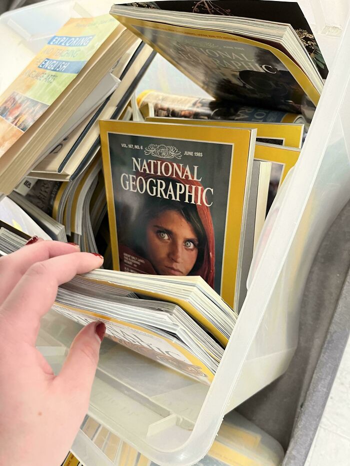 Рука листает стопку журналов National Geographic в ящике