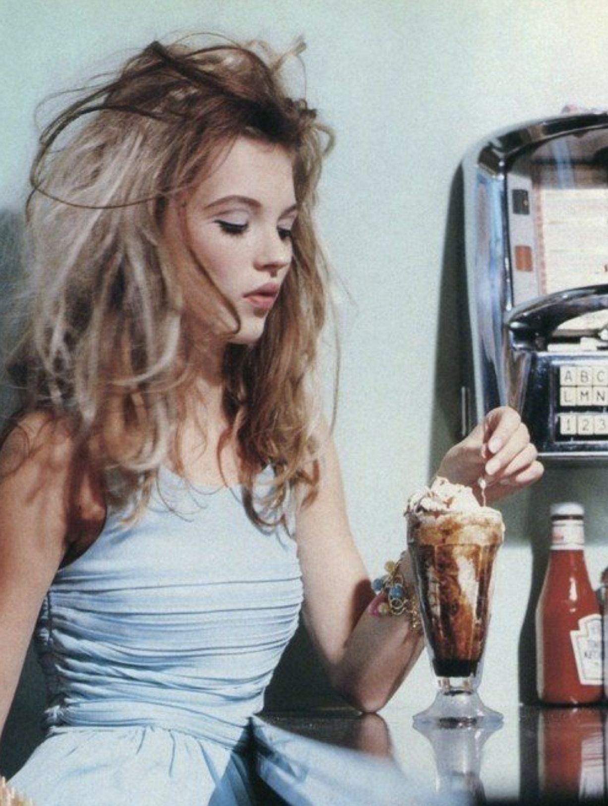 Kate Moss sitting at a diner counter with a milkshake, photographed by Lance Staedler for French Glamour in April 1992