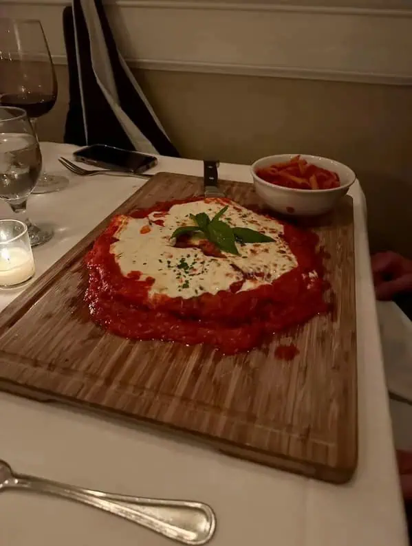 Курица пармиджано с томатным соусом и сыром на необработанной деревянной доске