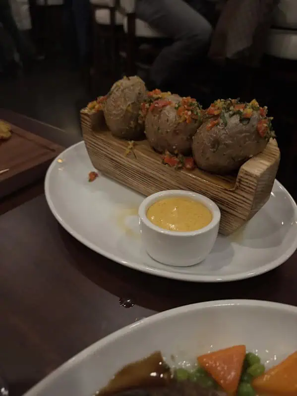 Три запечённые картофелины с соусом в деревянной лодочке