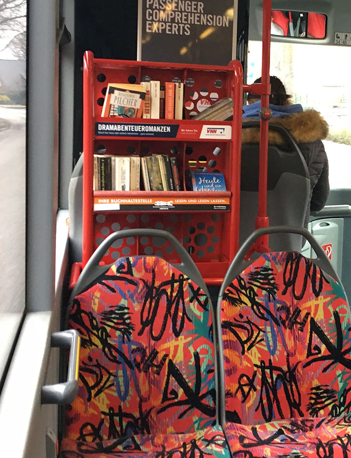 Красная книжная полка в салоне автобуса с узорчатыми сиденьями