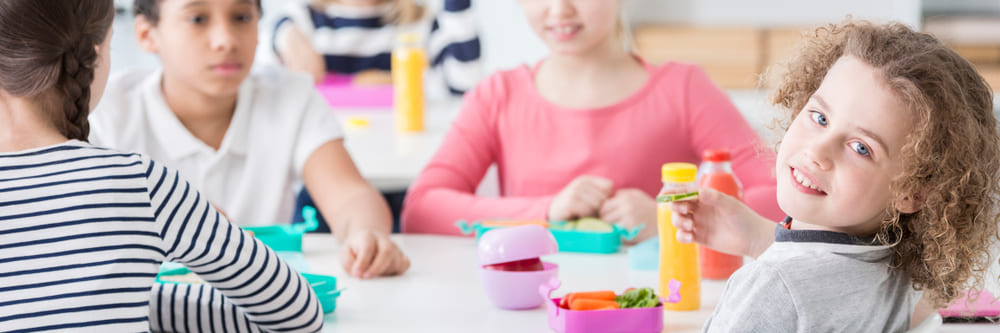 Group of kids eating vegetables for lunch in the school canteen during a break