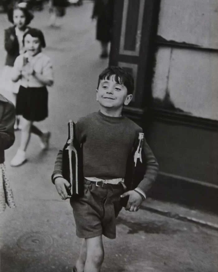 Мальчик несёт две большие бутылки по улице Муфтар. Париж, 1954 год. Фото Анри Картье-Брессона